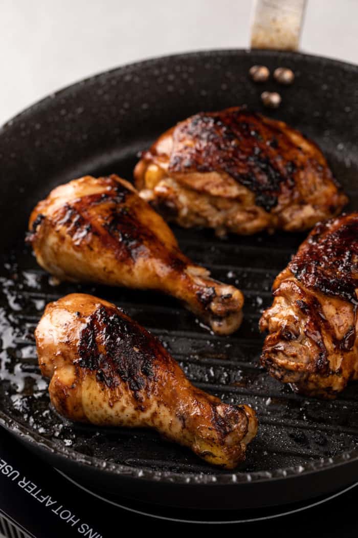 Several pieces of chicken being grilled in a grill pan.