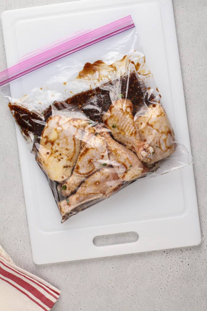 Raw chicken covered with the best grilled chicken marinade in a zip-top bag.