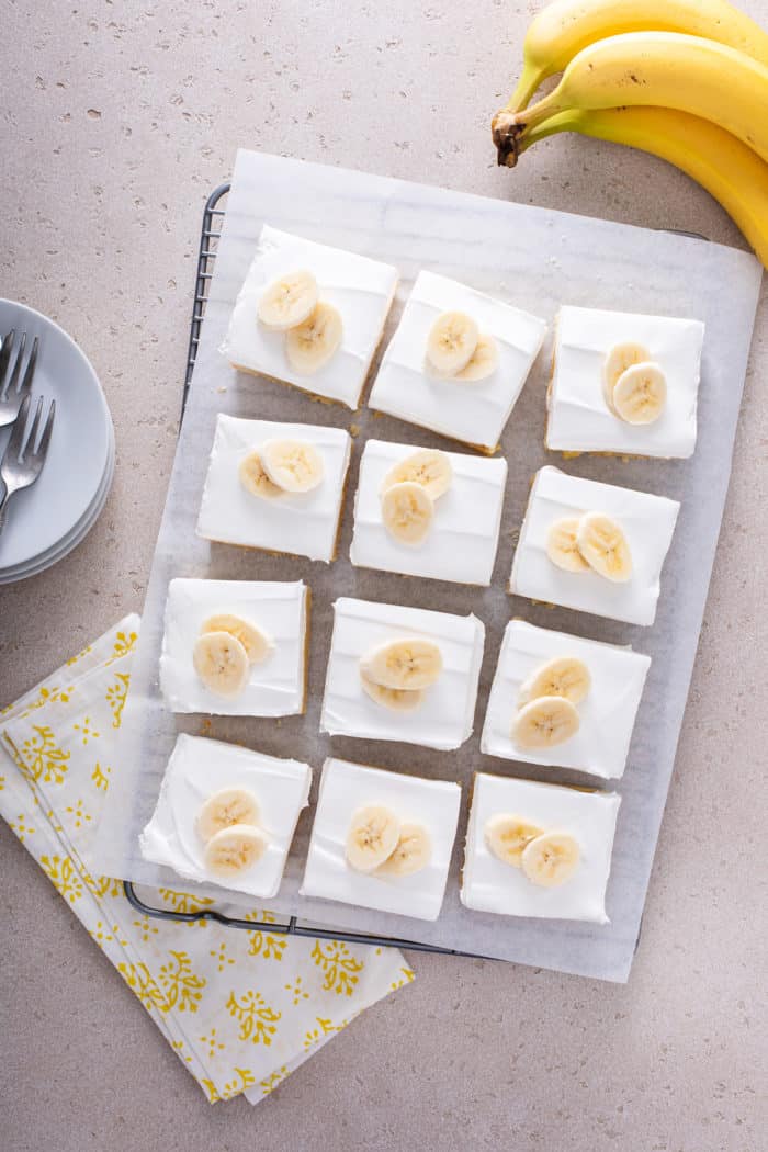 Overhead view of sliced banana cream bars, each topped with a piece of banana.