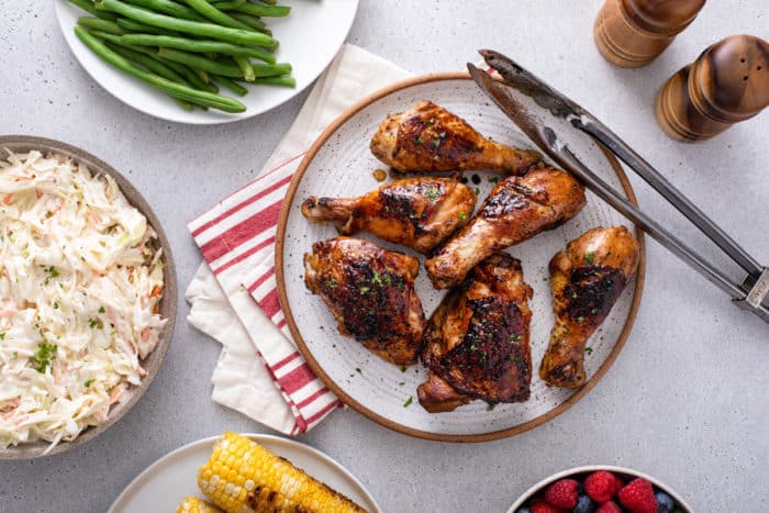 Overhead view of several pieces of grilled chicken on a platter, surrounded by various veggie sides.