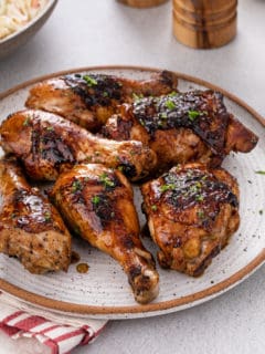 Various cuts of grilled chicken piled onto a stoneware platter.