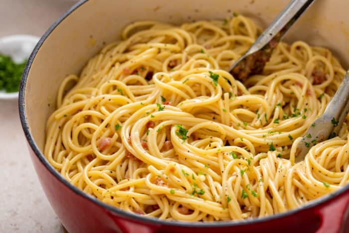 Red dutch oven filled with finished pasta carbonara.