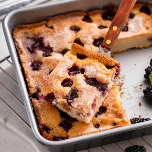 Cake server lifting a slice of easy blackberry cobbler out of the pan.