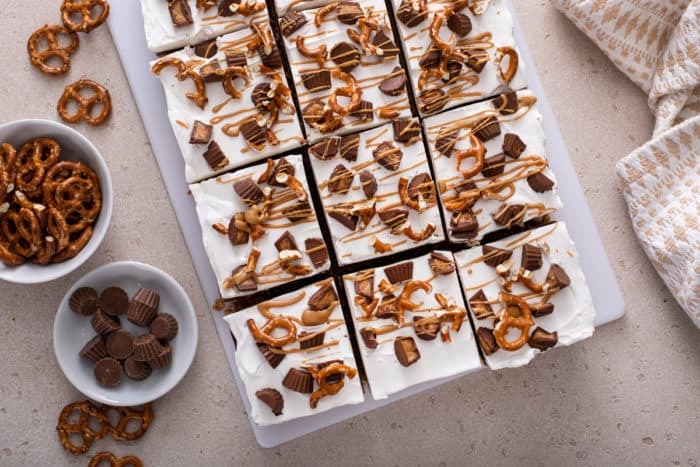 Overhead view of sliced peanut butter pretzel dessert on a light-colored countertop.