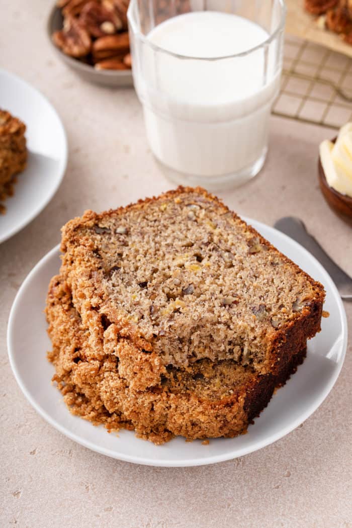 Stack of three slices of banana nut bread on a white plate with a bite taken from the top slice.