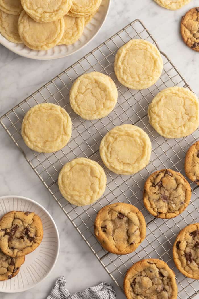 Perfectly round sugar cookies and chocolate chip cookies on a wire cooling rack.