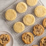 Assorted perfectly round sugar cookies and chocolate chip cookies on a wire cooling rack.