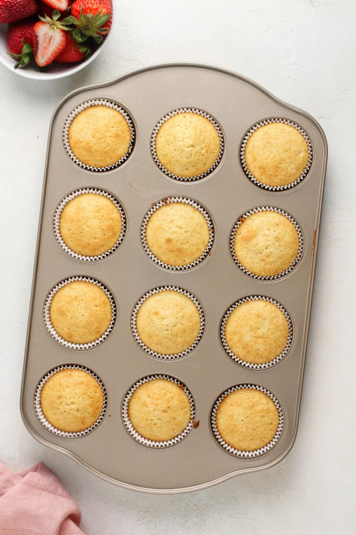 Baked shortcake cupcakes in a muffin tin, ready to be filled and frosted.