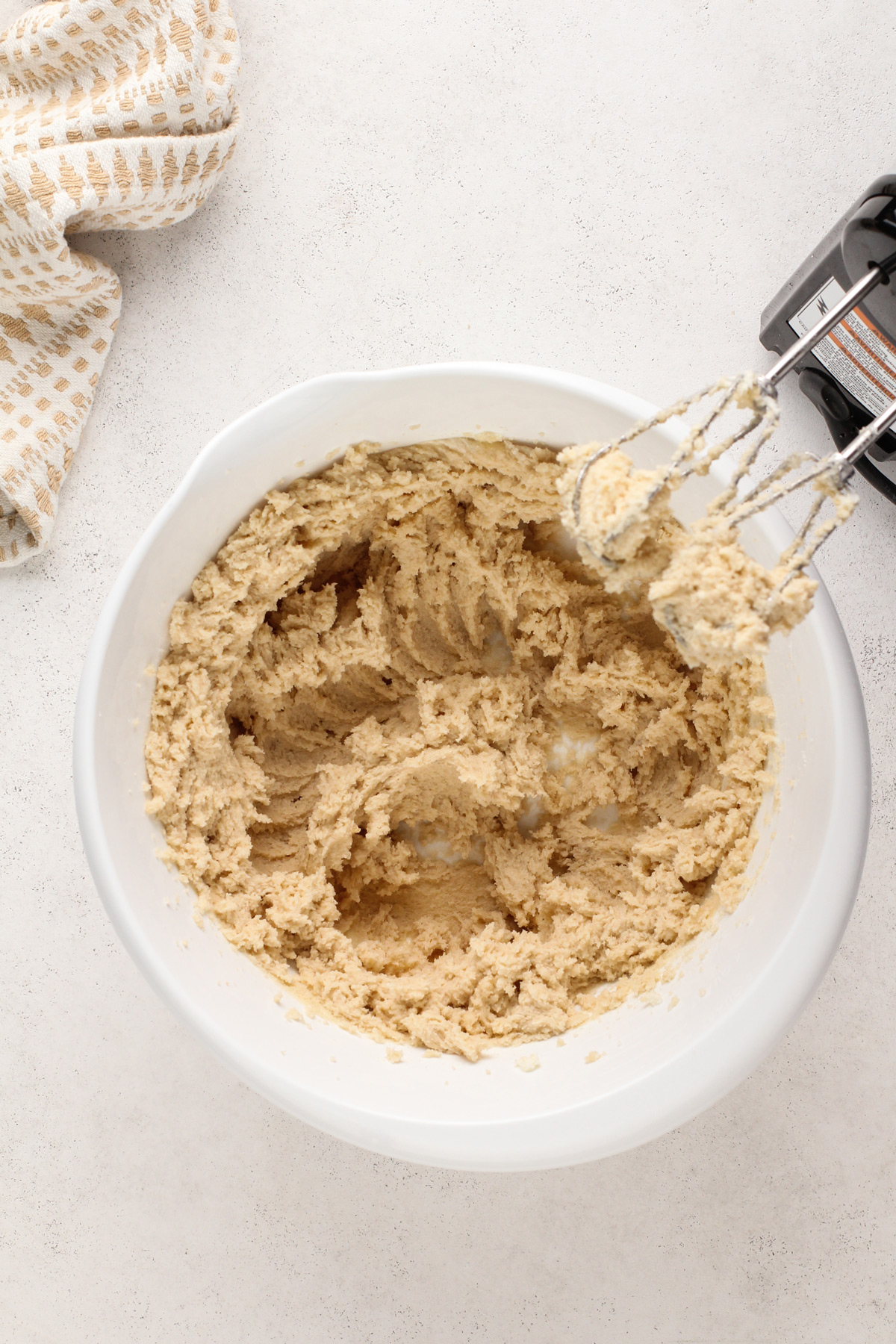 Butter and sugars beaten together in a white mixing bowl for cowboy cookies.