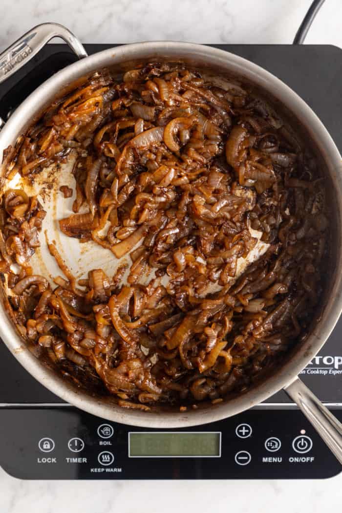 Caramelized onions in a large skillet set over an induction burner.