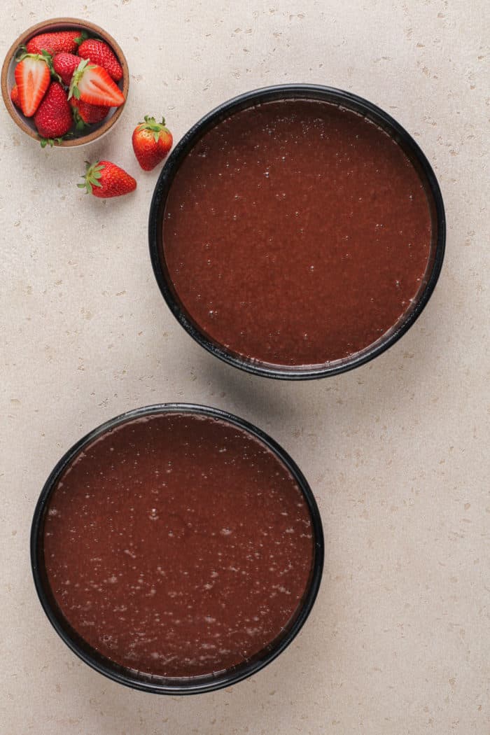 Chocolate cake batter in two 9-inch cake pans, ready to go in the oven.