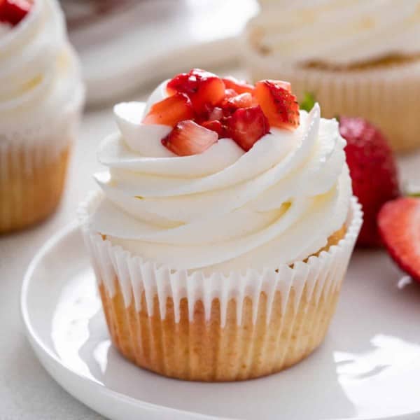 Close up of strawberry shortcake cupcake on a white plate.