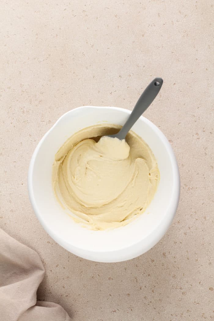 Batter base for easy peach coffee cake in a white mixing bowl, ready for the peaches to be added.