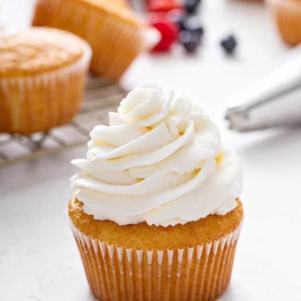 Close up of a vanilla cupcake topped with whipped cream frosting.