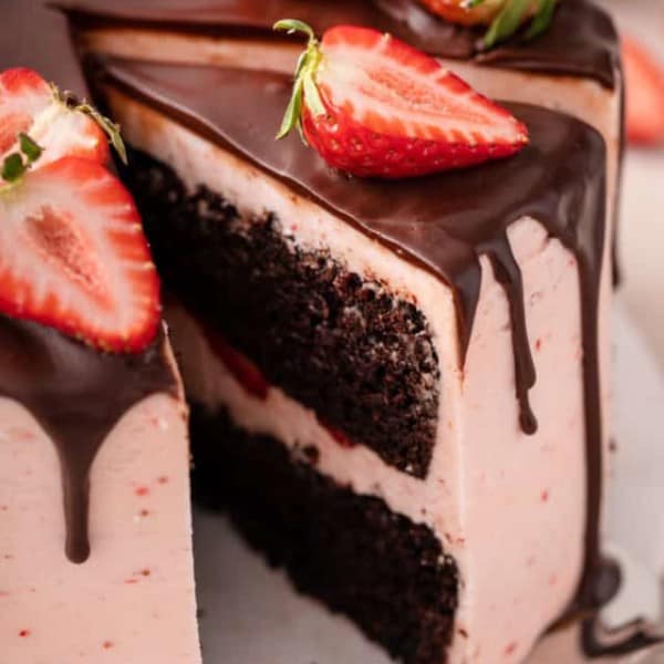Cake server lifting a slice of chocolate strawberry cake off of a cake plate.