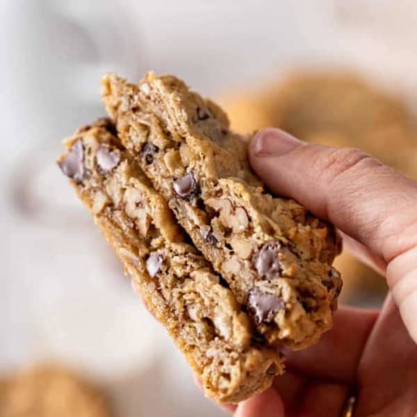 Halved cowboy cookie being held up to the camera to show the inside texture of the cookies.