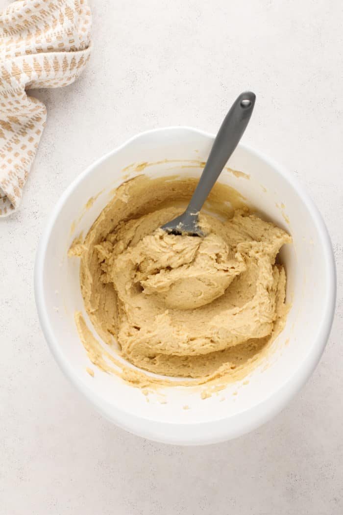 Eggs added to cowboy cookie dough in a white bowl, ready for the dry ingredients to be added.