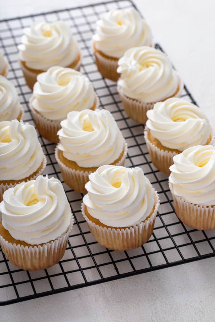 Shortcake cupcakes on a wire rack, frosted with whipped cream frosting.