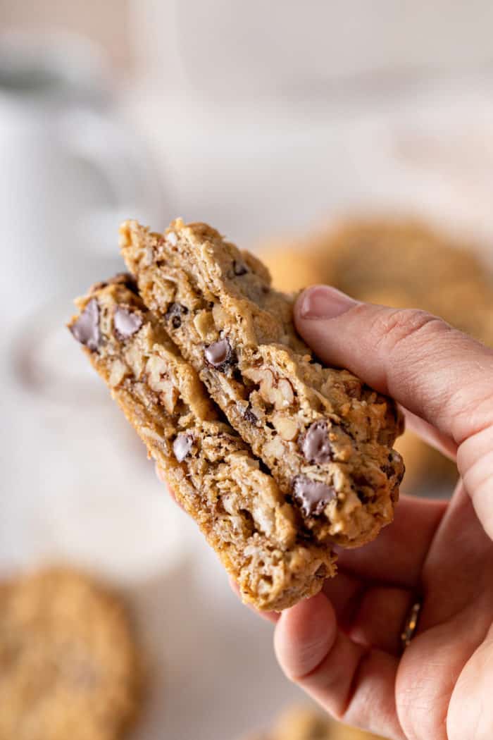 Halved cowboy cookie being held up to the camera to show the inside texture of the cookies.