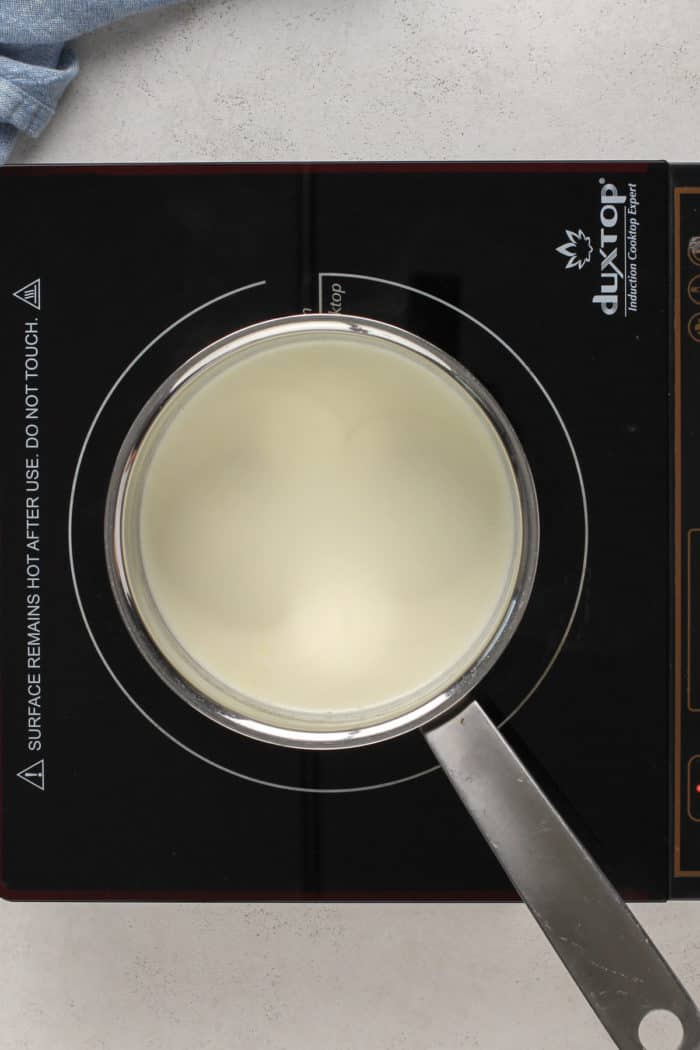 Heavy cream in a saucepan set on an induction burner.