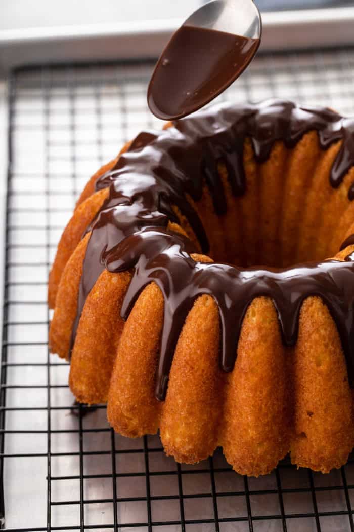 Chocolate ganache being spooned over a bundt cake.
