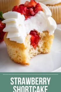 Half of a strawberry shortcake cupcake on a white plate, showing the diced strawberries in the center. Text overlay includes recipe name.