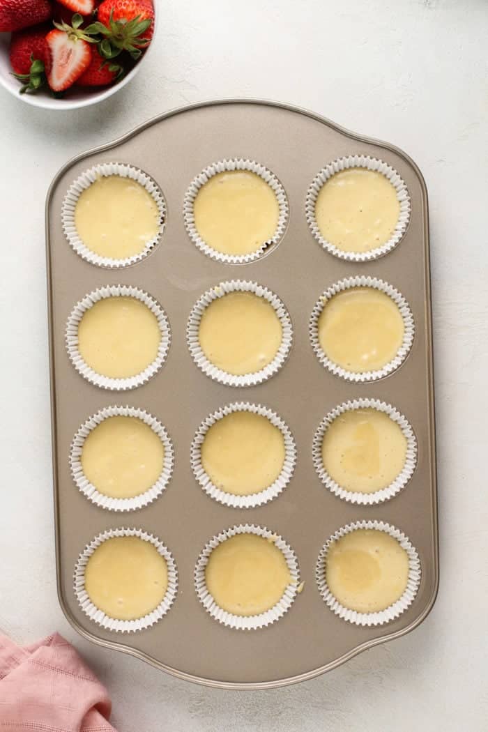 Batter for shortcake cupcakes divided between lined cupcake wells, ready to go in the oven.