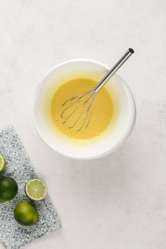 Eggs and sugar whisked together in a white mixing bowl.