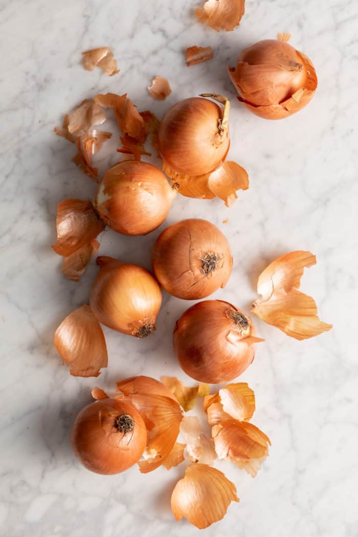 Yellow onions scattered across a marble countertop.