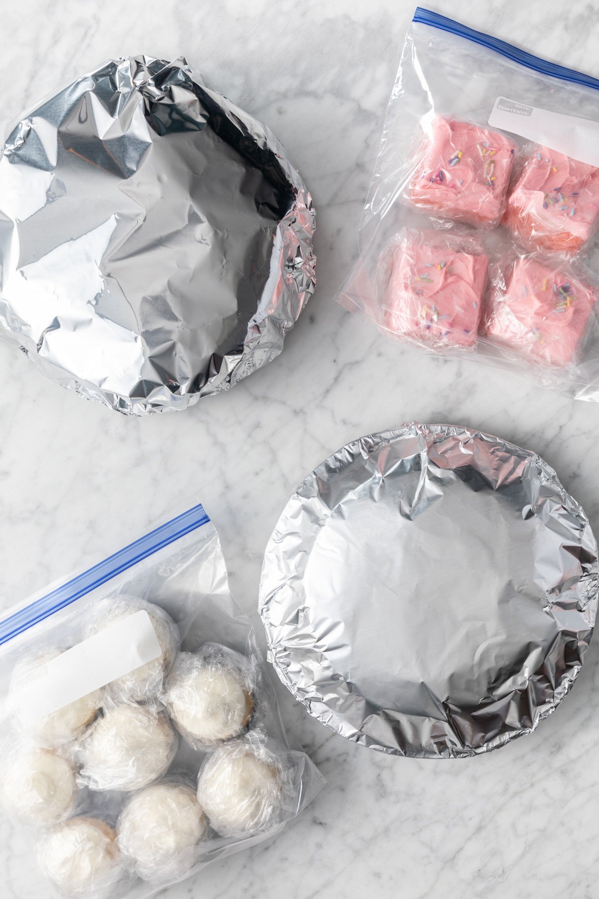 Assortment of wrapped cakes and cupcakes ready to go in the freezer.