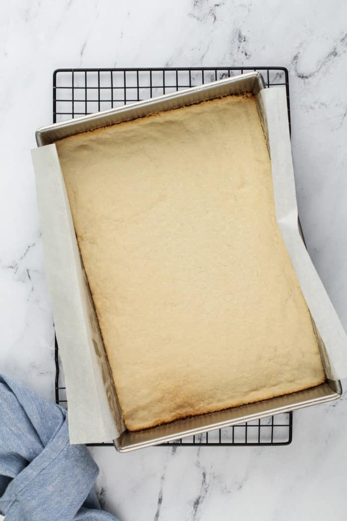 Baked crust for layered lemon dessert cooling on a wire rack.