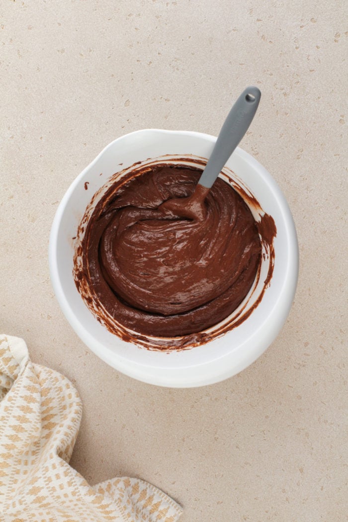 Batter for chocolate cake in a white mixing bowl.