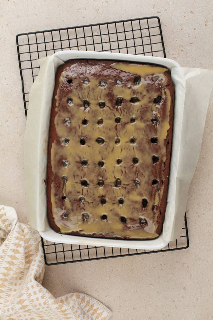 Chocolate cake in a 13x9-inch pan. The cake has holes poked in it and condensed milk and caramel poured over the top.