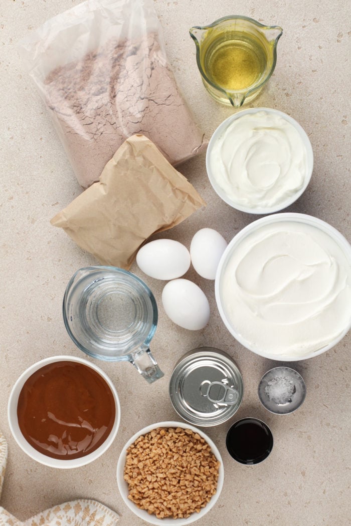 Chocolate toffee poke cake ingredients arranged on a beige countertop.