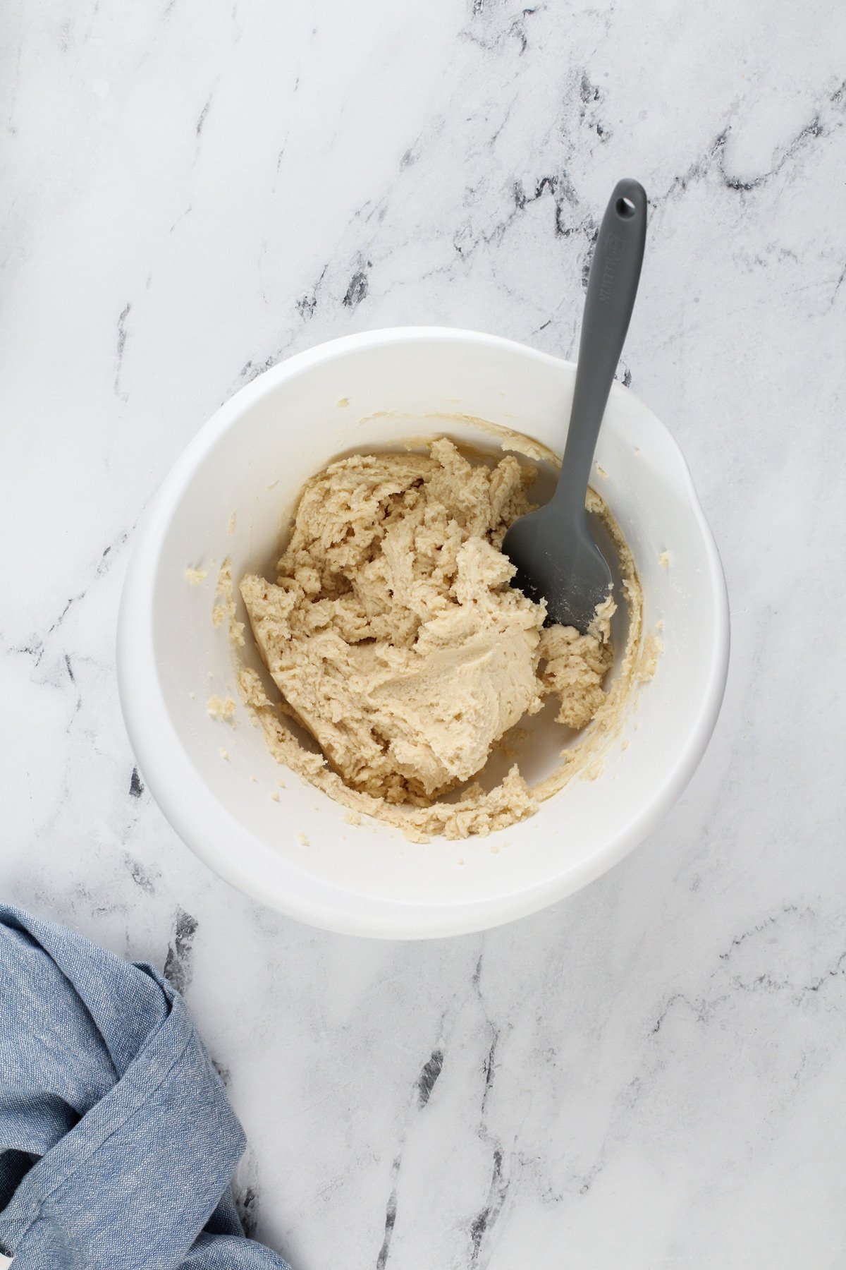 Dough for the crust for layered lemon dessert in a white mixing bowl.