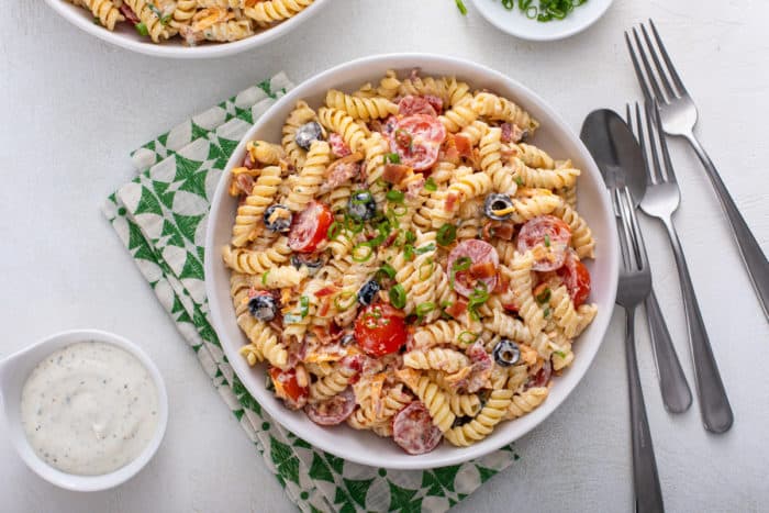 White bowl of bacon ranch pasta salad set on a green and white napkin.