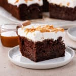 Slice of chocolate toffee poke cake on a white plate.