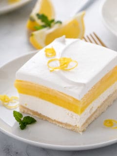 Close up image of a slice of layered lemon dessert on a white plate.