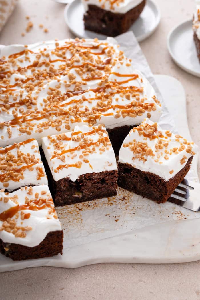 Sliced chocolate toffee poke cake on a piece of parchment paper.