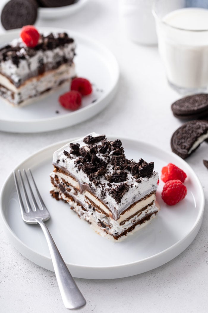 Two white plates, each holding a slice of ice cream sandwich cake. A glass of milk is visible in the background.