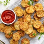 Breaded air fryer zucchini chips on a parchment-lined baking sheet.