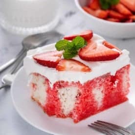 Slice of strawberry poke cake with a bite taken from it.
