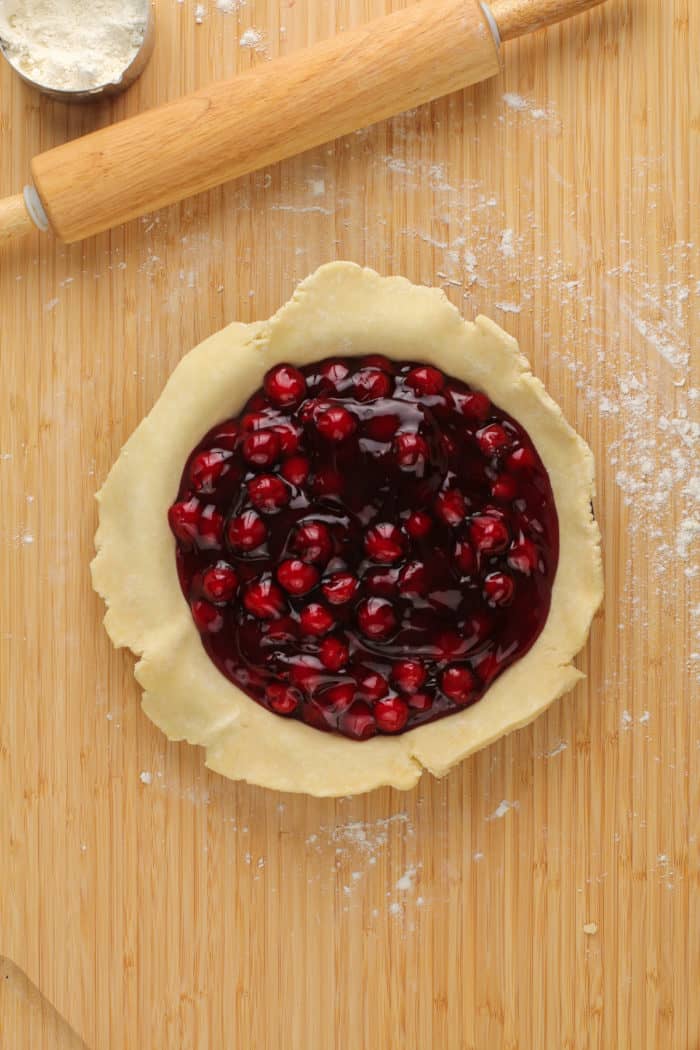 Homemade cherry pie filling in a pie plate on a wooden board.