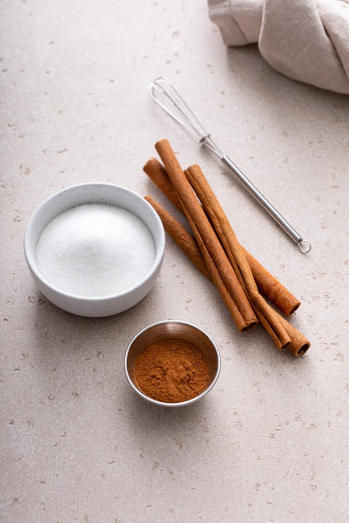 Ingredients for cinnamon sugar on beige countertop.