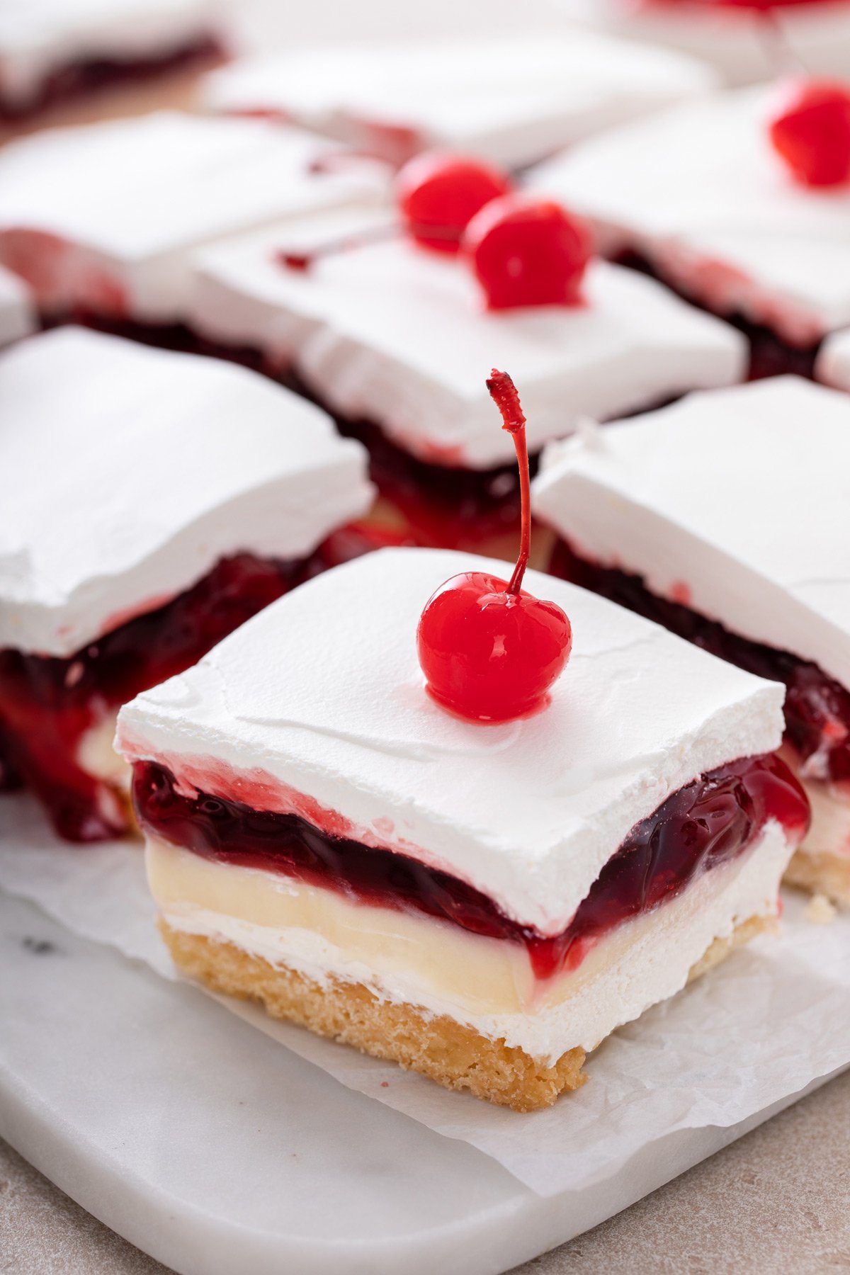 Close up of a slice of layered cherry cheesecake dessert on a platter.