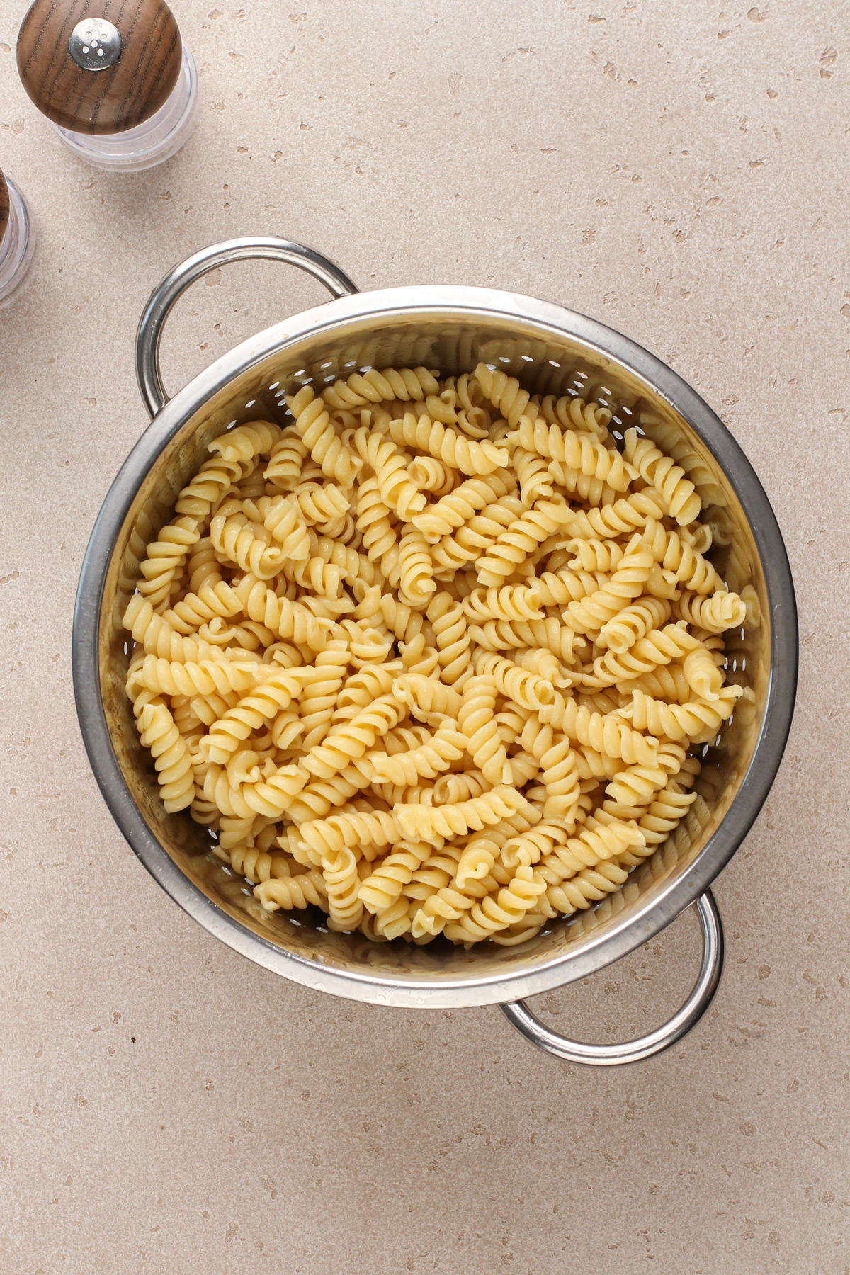 Cooked rotini pasta in a a metal collander.