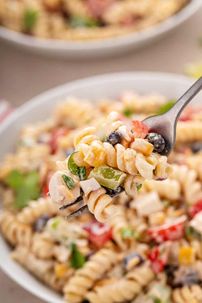 Pasta and mix-ins for southwest pasta salad arranged on a beige countertop.