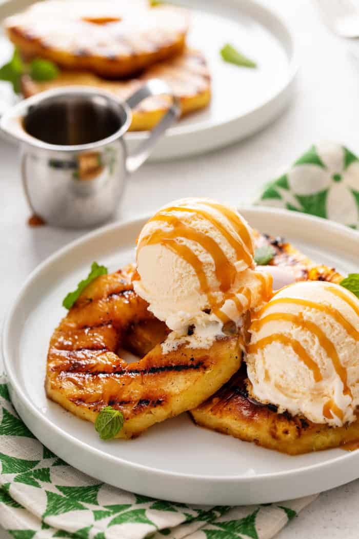 Slices of grilled pineapple topped with vanilla ice cream and drizzled with caramel sauce.