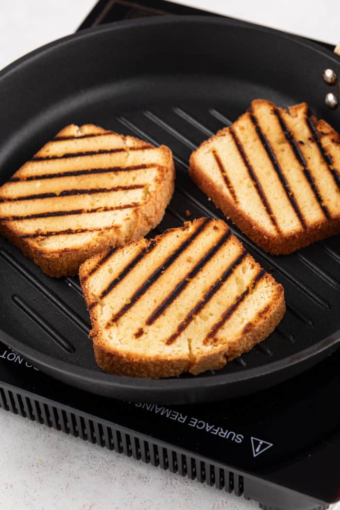 Three slices of pound cake being grilled in a grill pan.