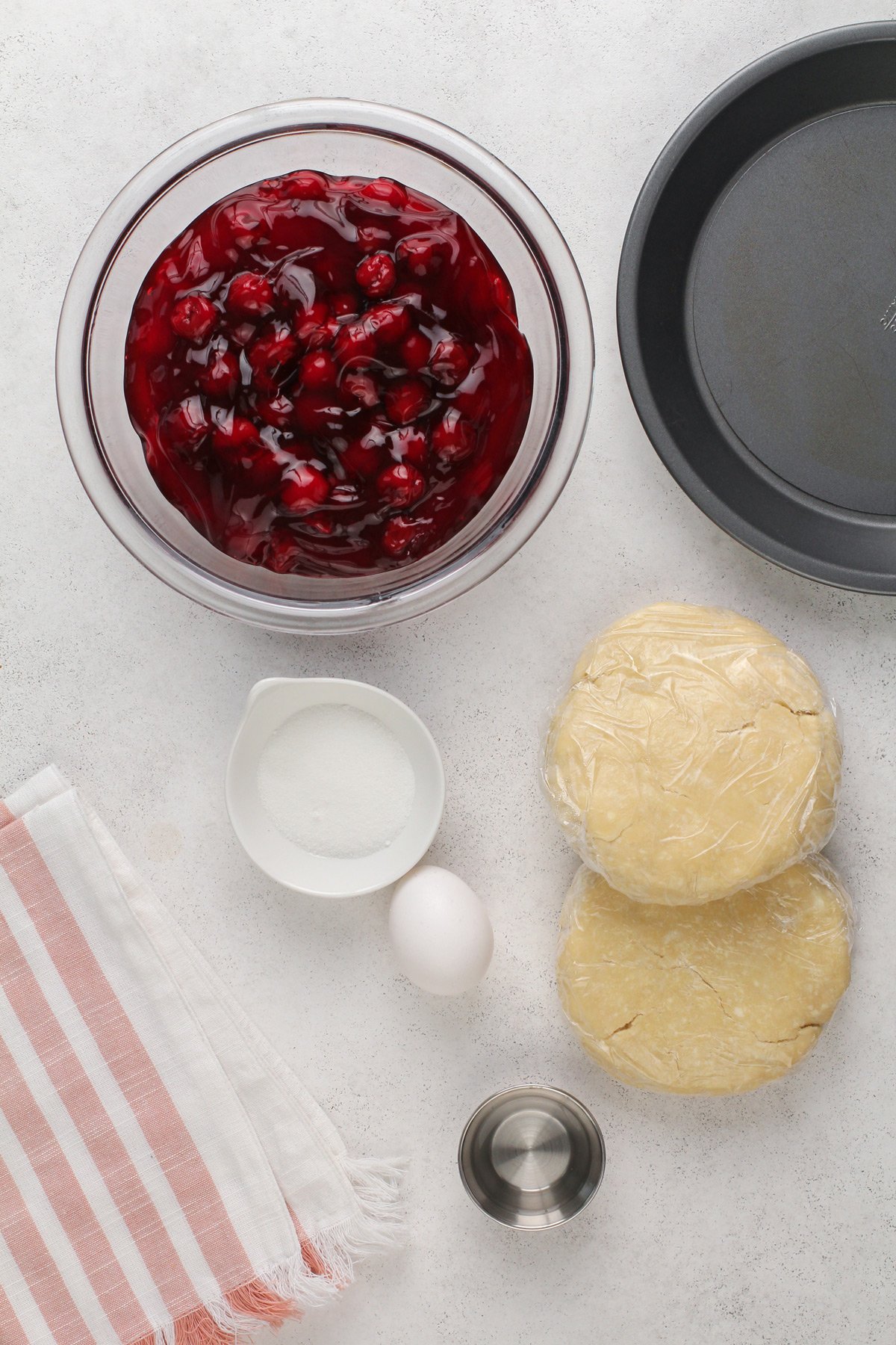 Homemade cherry pie ingredients arranged on a light countertop.